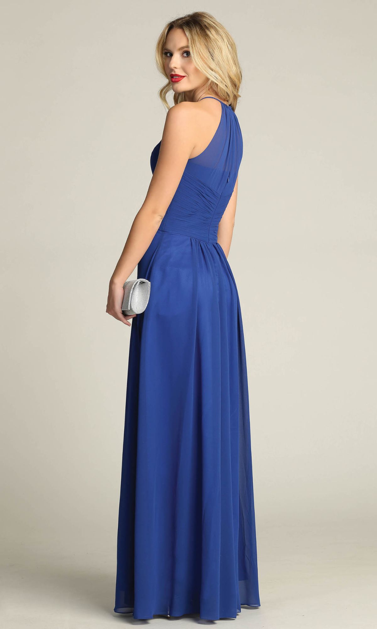 A woman faces away from the camera, elegantly holding a silver clutch while wearing the High-Neck Long A-Line Prom Dress: Chicas C5150, a sleeveless, floor-length royal blue gown.